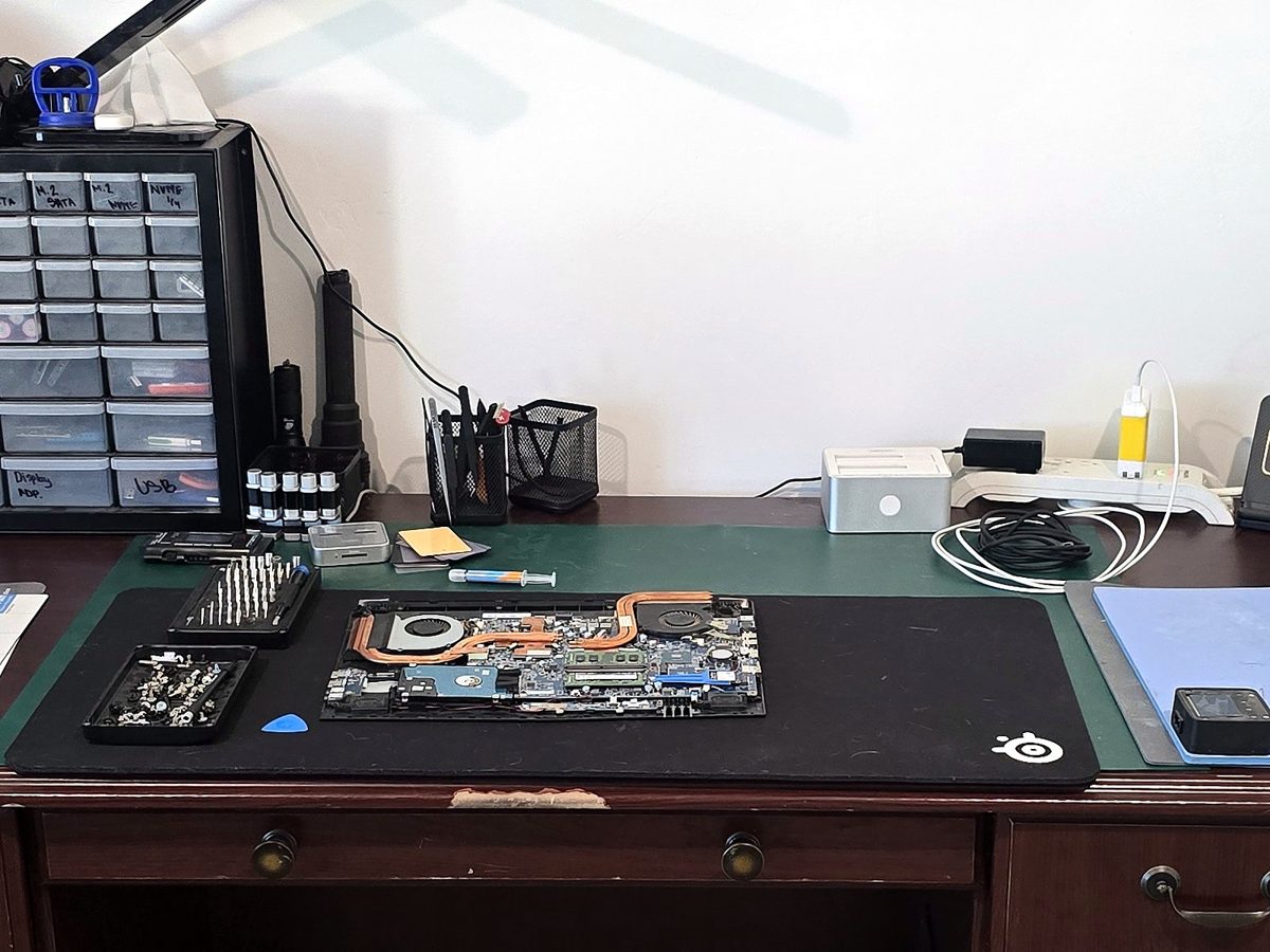 A laptop opened up for repair on our bench, with its cooling pipes and fans showing
